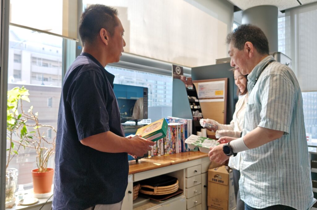 電子レンジの待ち時間に商品を見せ合いながら会話する社員